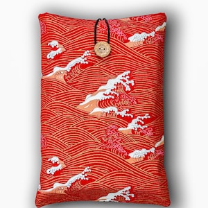 May include: Red cushion cover with a Japanese wave pattern. The design features white waves with peach accents against a red background with gold lines. A wooden button and black cord closure are at the top.