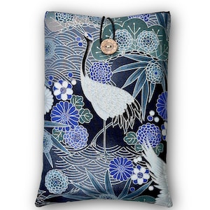 Könnte beinhalten: Eine rechteckige Kissenhülle mit einem japanischen Kranich-Design. Die Hülle hat einen dunkelblauen Hintergrund mit weißen, blauen und türkisfarbenen Blumen- und Wellenmustern. Ein Holzknopf und eine schwarze Kordel sichern die Oberseite.
