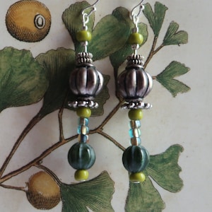 May include: Silver and green dangle earrings with a silver bead, green beads, and a blue and silver bead.