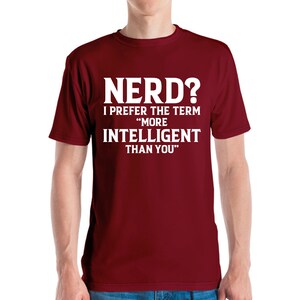 May include: A maroon t-shirt with the text "NERD? I PREFER THE TERM 'MORE INTELLIGENT THAN YOU'" in white block letters. The shirt is a crew neck style and appears to be made of a soft material.