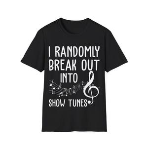 May include: Black t-shirt with the white text: "I randomly break out into show tunes." A musical staff with notes and a treble clef are below the text. The shirt has a crew neck.