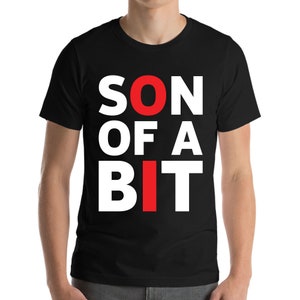 Może przedstawiać: Czarny t-shirt z napisem "SON OF A BIT" dużymi białymi literami. Litery "O" i "I" są czerwone. Koszulka wykonana jest z miękkiego materiału.