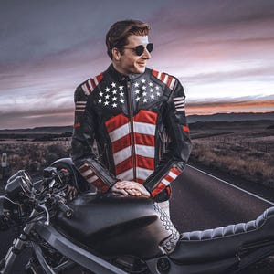 May include: Black leather motorcycle jacket with a red and white striped design on the front, and white stars on the shoulders. The jacket is worn by a person standing next to a black motorcycle on a road.