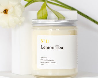 Peut inclure: Un bocal de bougie blanc avec un couvercle argenté. L'étiquette indique "N" 11 Lemon Tea" et comprend le texte "By Mia's Co. 100% Soy Wax Candle Handcrafted in California 7.5 oz".