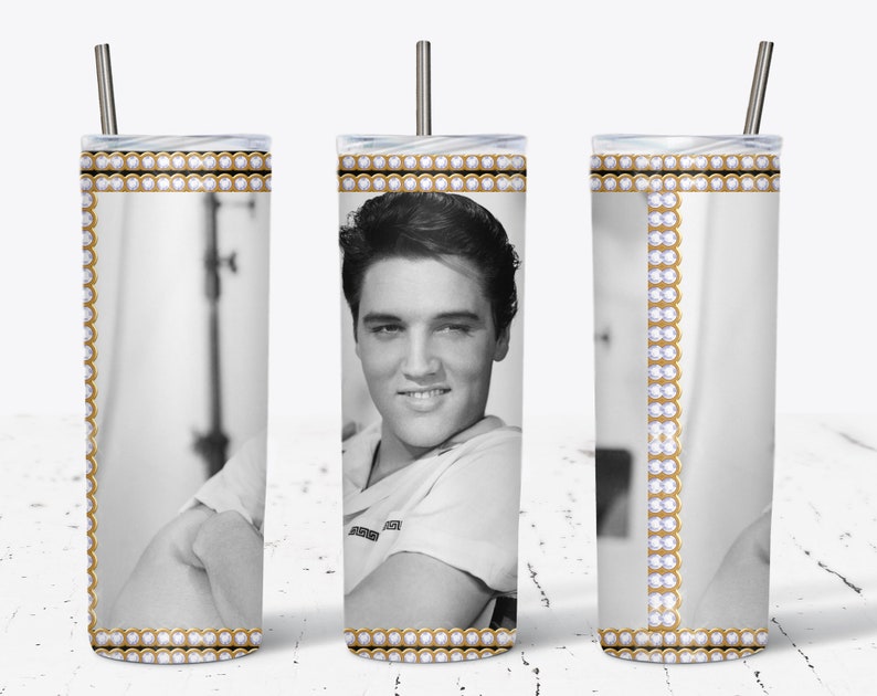 May include: A stainless steel tumbler featuring a black and white image of Elvis Presley. The tumbler has a gold and white decorative border with a silver straw. The design wraps around the entire tumbler.