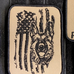 May include: A tan embroidered patch with a black German Shepherd dog silhouette in front of an American flag.