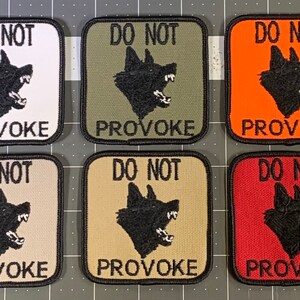 May include: Six square patches with black borders and white, green, orange, beige, tan, and red backgrounds. Each patch features a black silhouette of a snarling dog's head and the text "DO NOT PROVOKE" in black.