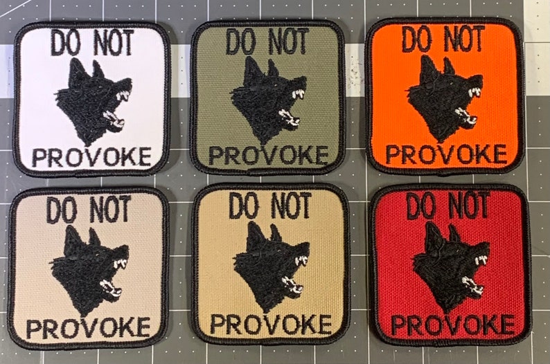 May include: Six square patches with black borders and white, green, orange, beige, tan, and red backgrounds. Each patch features a black silhouette of a snarling dog's head and the text "DO NOT PROVOKE" in black.