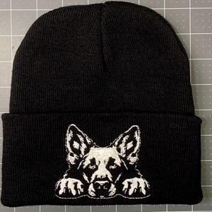 May include: Black knit beanie with a white embroidered German Shepherd peeking out from the bottom.