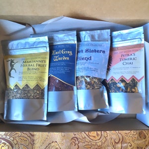 May include: Four silver pouches of loose leaf tea with labels. The labels are black with white text and list the tea blends: Marianne's Herbal Fruit Blend, Earl Gray Warden, Sweet Sisters Blend, and Petra's Turmeric Chai.