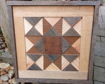 May include: A framed wooden wall art piece with a geometric design. The design is made up of various shades of brown wood, creating a starburst pattern.