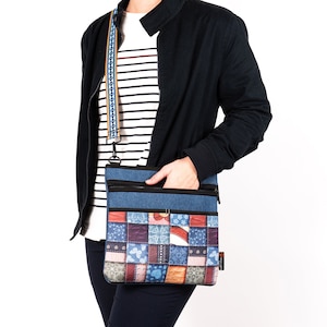 Puede incluir: Un bolso bandolera azul y marrón de patchwork con cierre de cremallera y una larga correa ajustable. El bolso tiene un diseño de patchwork colorido con varios patrones y texturas.