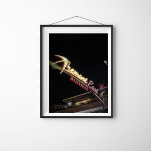 Peut inclure: Photographie encadrée du néon du quartier de Fremont East la nuit. L'enseigne est jaune et rouge avec une étoile et les mots "Fremont East District". La photographie est prise d'en bas.