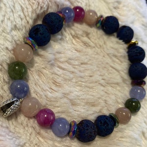 Peut inclure: Un bracelet composé de perles de lave roche bleu foncé, de perles de pierres précieuses roses, vertes et bleues, et d'accents argentés.