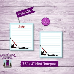 May include: A personalized 3.5 x 4 inch mini notepad with 25 sheets. The notepad features a hockey stick and puck design with a blue and white striped background. The text "Jake" is printed on the notepad.