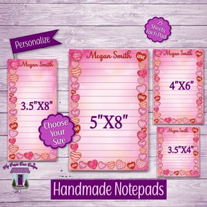 May include: Handmade notepads in various sizes, featuring a pink gradient background and a border of hearts. Each notepad is personalized with a name and includes the text "Love" and "Hugs". Sizes include 3.5"x8", 5"x8", 4"x6", and 3.5"x4".