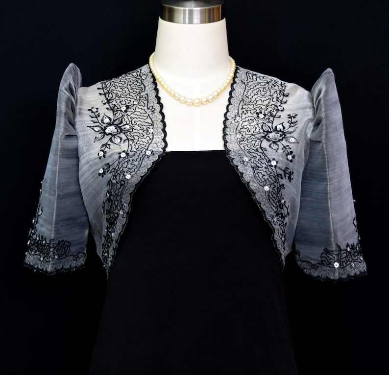 Our Silver/Black Traje de Mestiza Embroidered Bolero is a testament to understated beauty. Crafted from  Organza fabric, with a butterfly sleeves, delicate floral design & a refined standing collar that adds  a touch of timeless charm to any occasion
