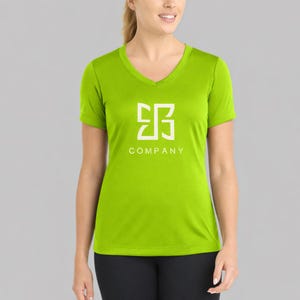 May include: A lime green V-neck t-shirt with a white logo and the word "COMPANY" printed below it. The logo is a stylized geometric design. The shirt is made of a soft, comfortable material.
