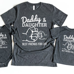 May include: Three gray shirts with white text that reads "Daddy & Daughter Best Friends For Life" and a fist bump graphic. The shirts are in different sizes, one is a baby onesie.