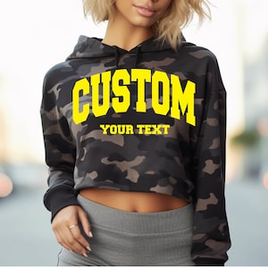 a woman wearing a camo hoodie with the word custom on it