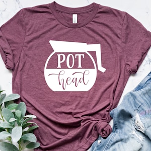 May include: A maroon t-shirt with a white graphic of a coffee pot with the text "POT head" inside.