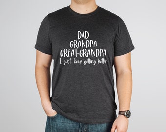 May include: A dark gray t-shirt with white text that reads "Dad Grandpa Great-Grandpa I just keep getting better".