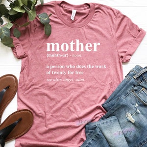 May include: A pink t-shirt with the word "mother" defined as "a person who does the work of twenty for free" in white text.