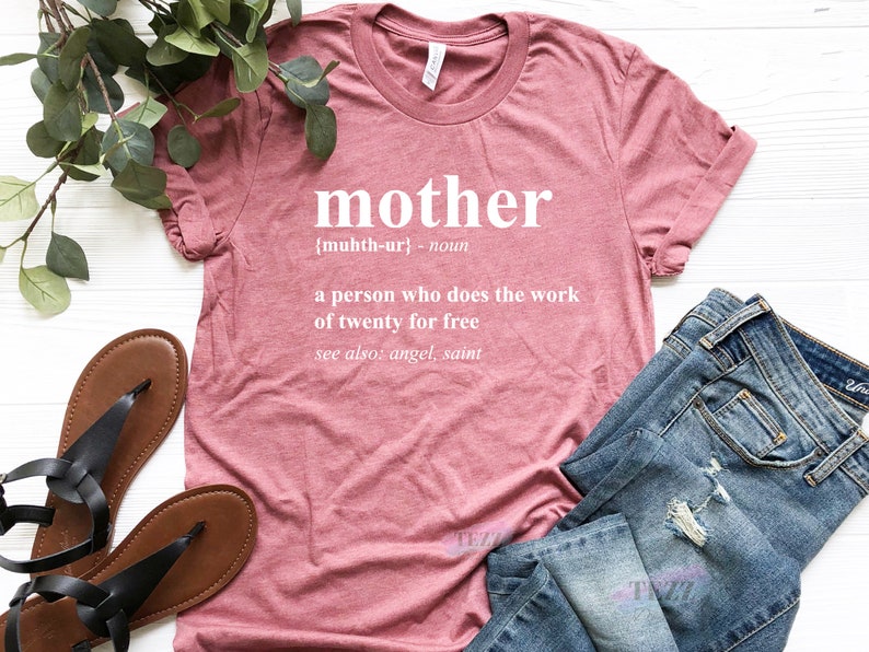 May include: A pink t-shirt with the word "mother" defined as "a person who does the work of twenty for free" in white text.
