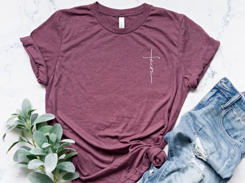 May include: A maroon t-shirt with a white cross and the word "faith" written vertically on the left side of the chest.
