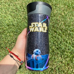 May include: A black and silver tumbler with a glittery finish. It features a Star Wars logo and a graphic of the character BB-8.