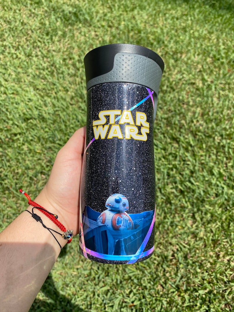 May include: A black and silver tumbler with a glittery finish. It features a Star Wars logo and a graphic of the character BB-8.