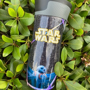 May include: A black and silver travel mug with a glittery finish. The mug features a Star Wars logo and a graphic of the character BB-8.