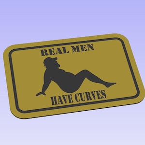May include: A gold-colored sign with black text and a silhouette of a person. The sign reads "REAL MEN HAVE CURVES".