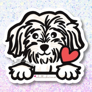May include: A sticker featuring a cartoon dog with black and white fur, holding a red heart. The sticker has the text "whattacharmer" in a script font.