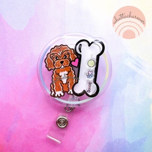 May include: A clear plastic badge holder featuring a brown and white cartoon dog and a white bone. The holder has a retractable badge reel.