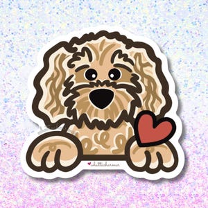 May include: A die-cut sticker featuring a tan, curly-haired dog with dark brown outlines, large black eyes, and a black nose. The dog is resting its front paws on a horizontal line, holding a red heart, with the text whattacharmer printed below.