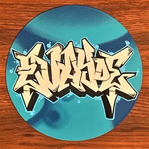 May include: A blue vinyl record with a white and black graffiti design that says "SKATE" in large letters.