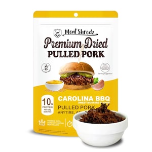May include: A yellow bag of Carolina BBQ Sweet Mustard Flavor Pulled Pork. The bag features a picture of a pulled pork sandwich and a bowl of dried pulled pork. The bag is labeled with the text "Meat Shredz Premium Dried Pulled Pork" and "10g Protein per 28g Serving".