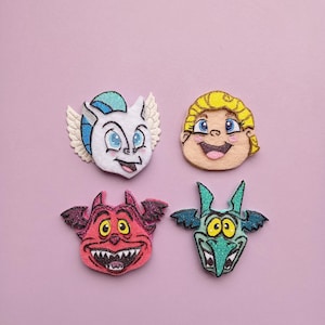 May include: Four felt appliques featuring characters from the Disney movie Hercules. The appliques are of Hercules, Pegasus, Pain, and Hades. The appliques are all in different colors and have a glitter finish.