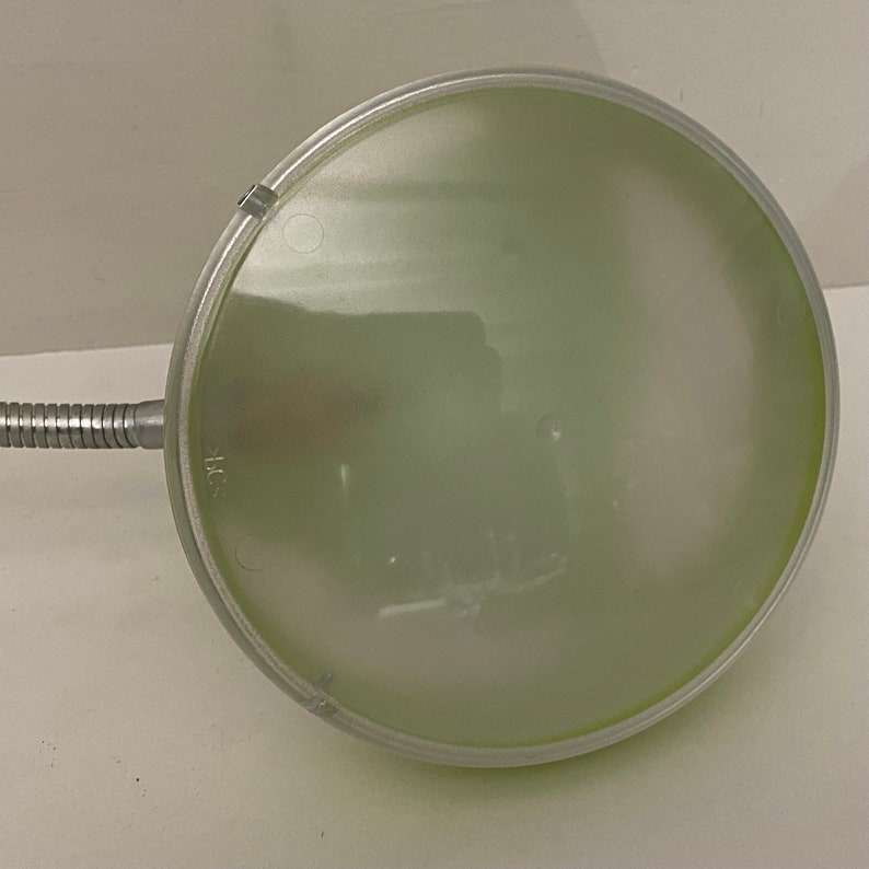 May include: A silver desk lamp with a green glass shade. The lamp has a flexible arm and a round base.