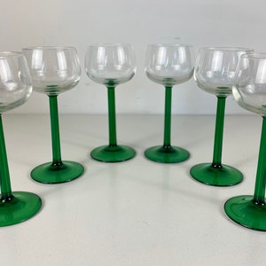 May include: Set of six clear glass wine glasses with green stems and bases.