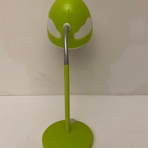 May include: A green desk lamp with a white cloud design on the shade. The lamp has a flexible arm and a round base.