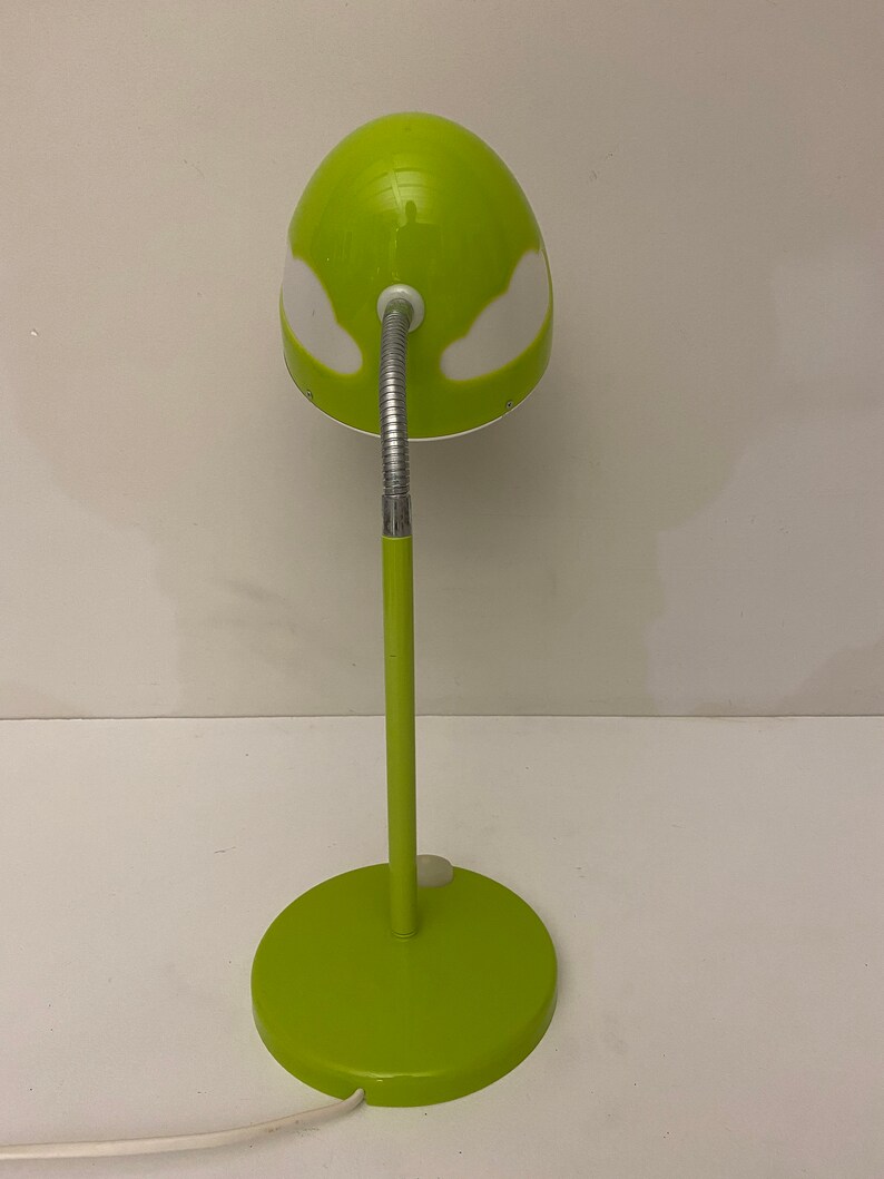 May include: A green desk lamp with a white cloud design on the shade. The lamp has a flexible arm and a round base.