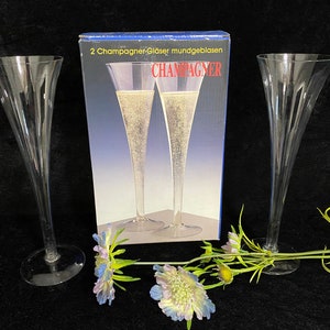 May include: Two clear glass champagne flutes with a box that says "2 Champagner-Gl&auml;ser mundgeblasen CHAMPAGNER" in German.