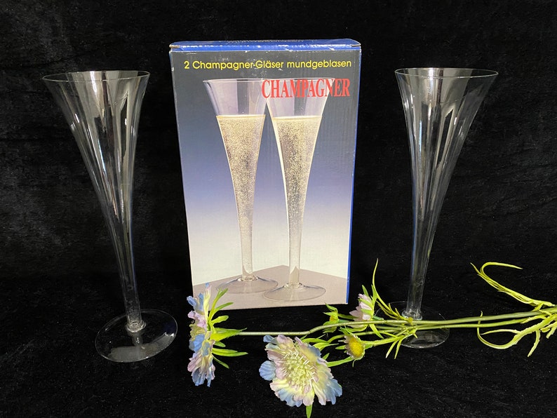 May include: Two clear glass champagne flutes with a box that says "2 Champagner-Gl&auml;ser mundgeblasen CHAMPAGNER" in German.