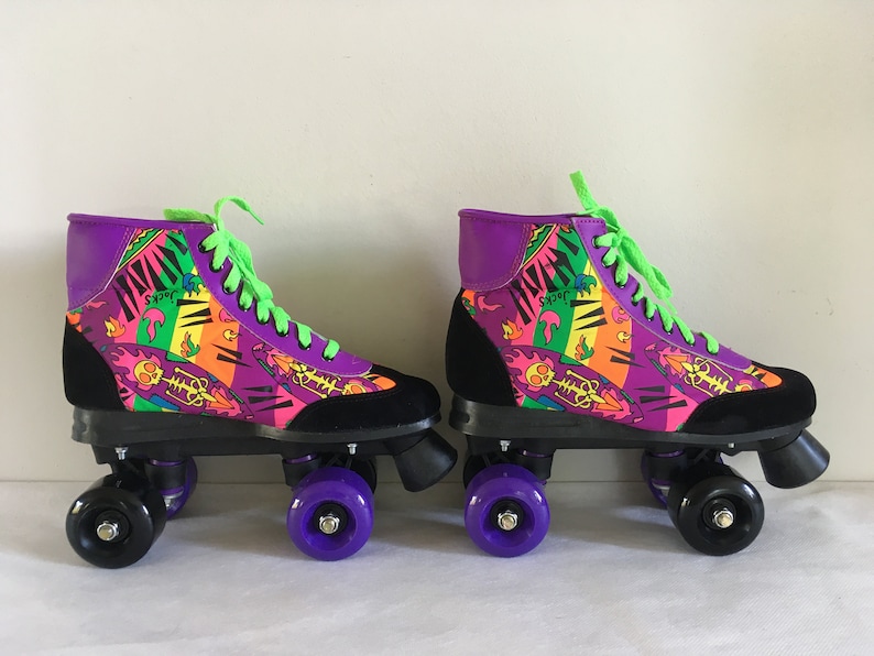 May include: A pair of purple, black, and neon green roller skates with a colorful, abstract print. The skates have black wheels with purple hubs.
