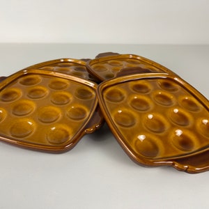 Op de afbeelding: Vier bruine keramische schalen met individuele inkepingen om hapjes of snacks te serveren.