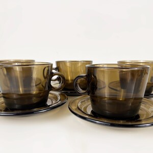 K&ouml;nnte beinhalten: Set aus f&uuml;nf braunen Glas-Teetassen und Untertassen. Die Tassen und Untertassen haben ein schlichtes, elegantes Design.