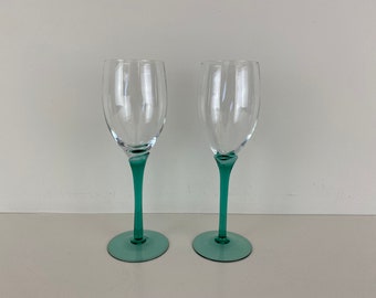May include: Two clear glass wine glasses with green stems and bases.