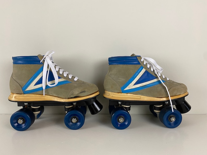 May include: A pair of vintage roller skates with gray suede boots, blue and white accents, and blue wheels.